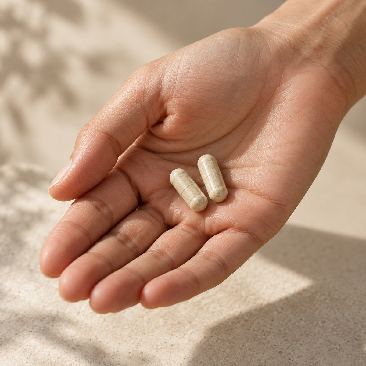 Illustrative close-up of a hand holding two intact supplement capsules